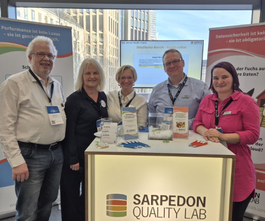 Frau steht am Rednerpult, Publikum applaudiert, Fenster mit Blick auf die Stadt im Hintergrund.